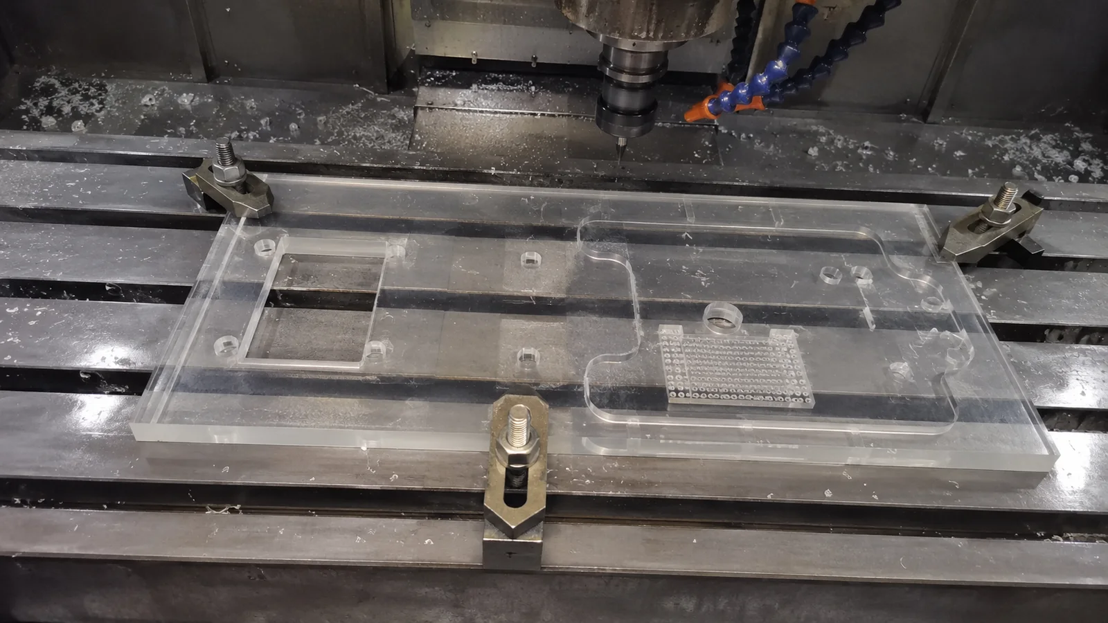 Clear acrylic panel held on a CNC fixture during machining
