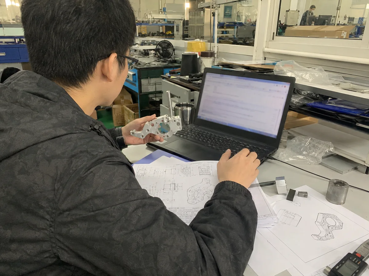 Engineer reviewing prototype drawings and CAD notes at a laptop