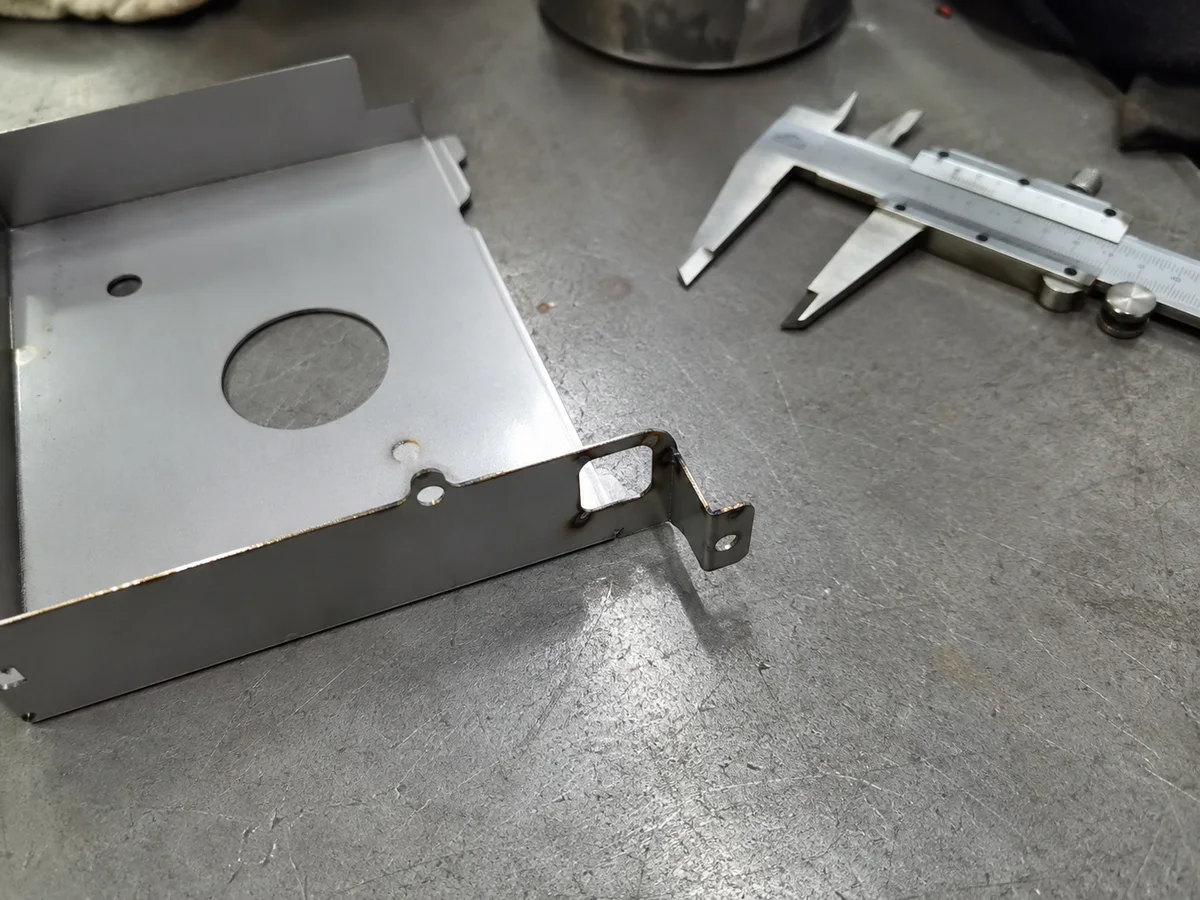 Laser cut metal bracket checked with calipers on a bench
