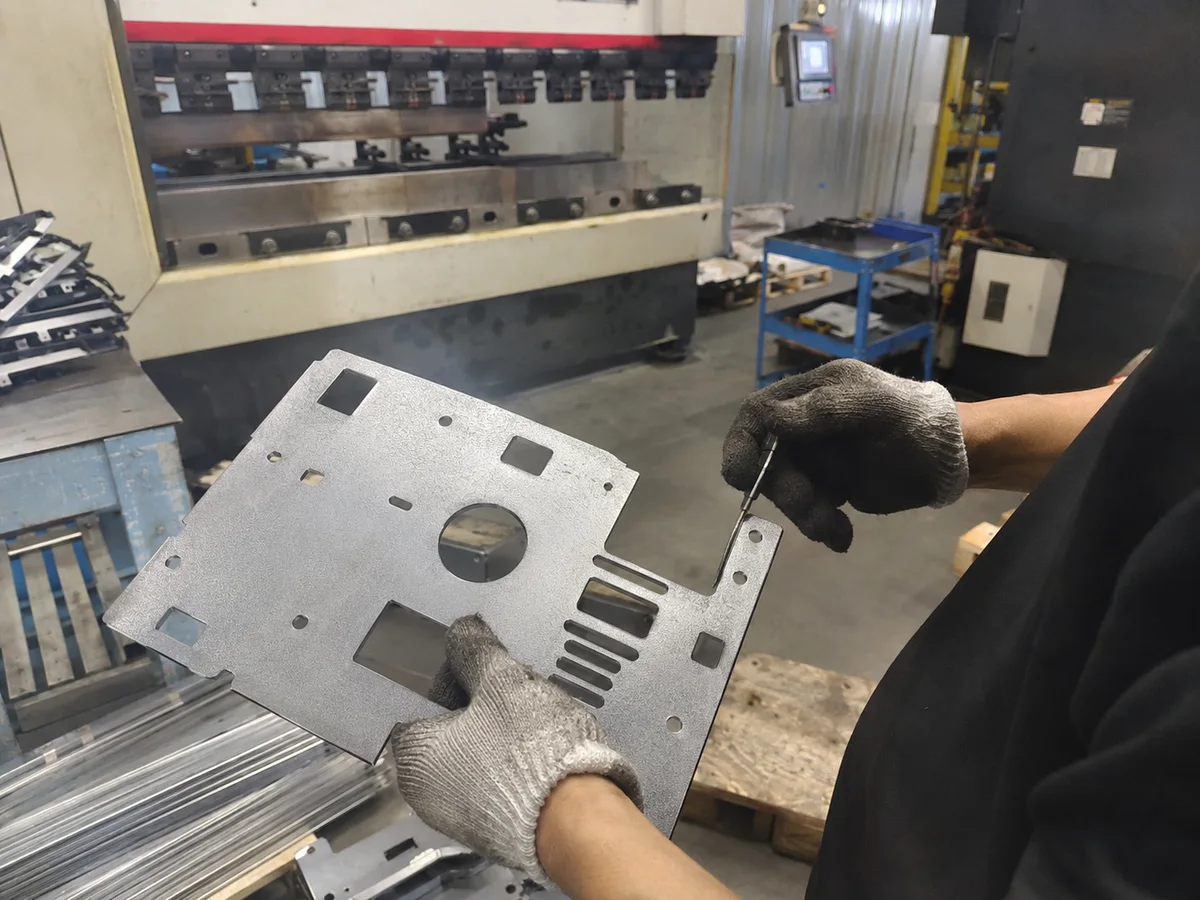 Worker reviewing a laser cut sheet metal panel after deburring