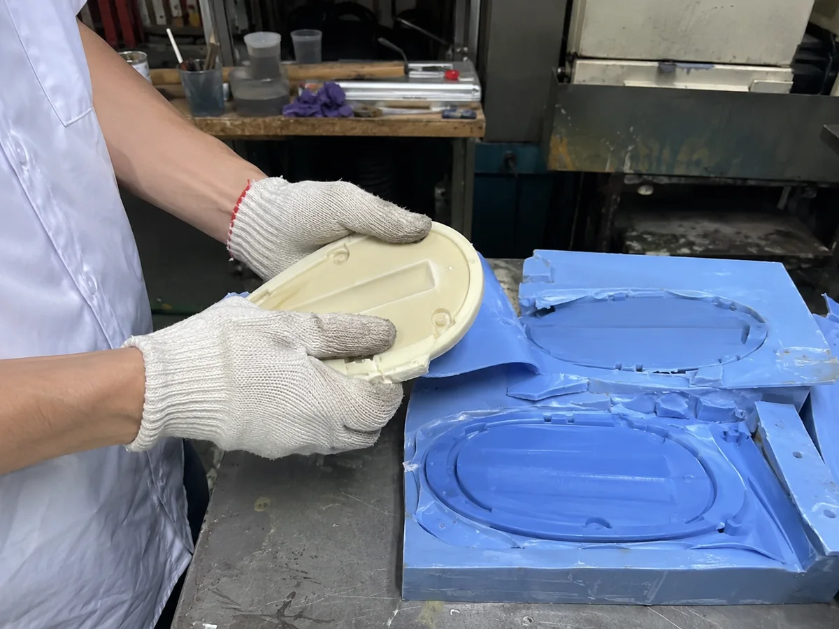 Worker demolding a urethane cast part from a blue silicone mold
